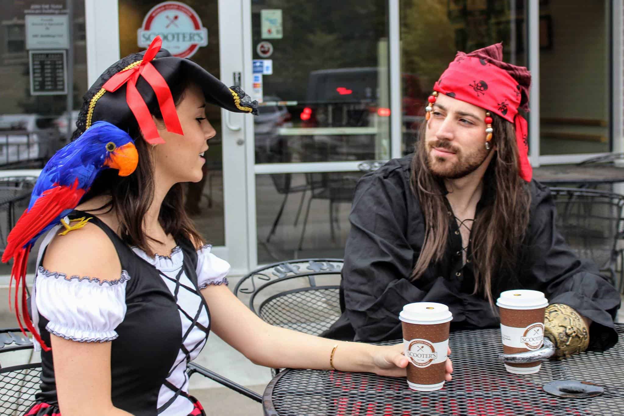 Man and woman dressed as pirates, drinking a coffee from Scooter's