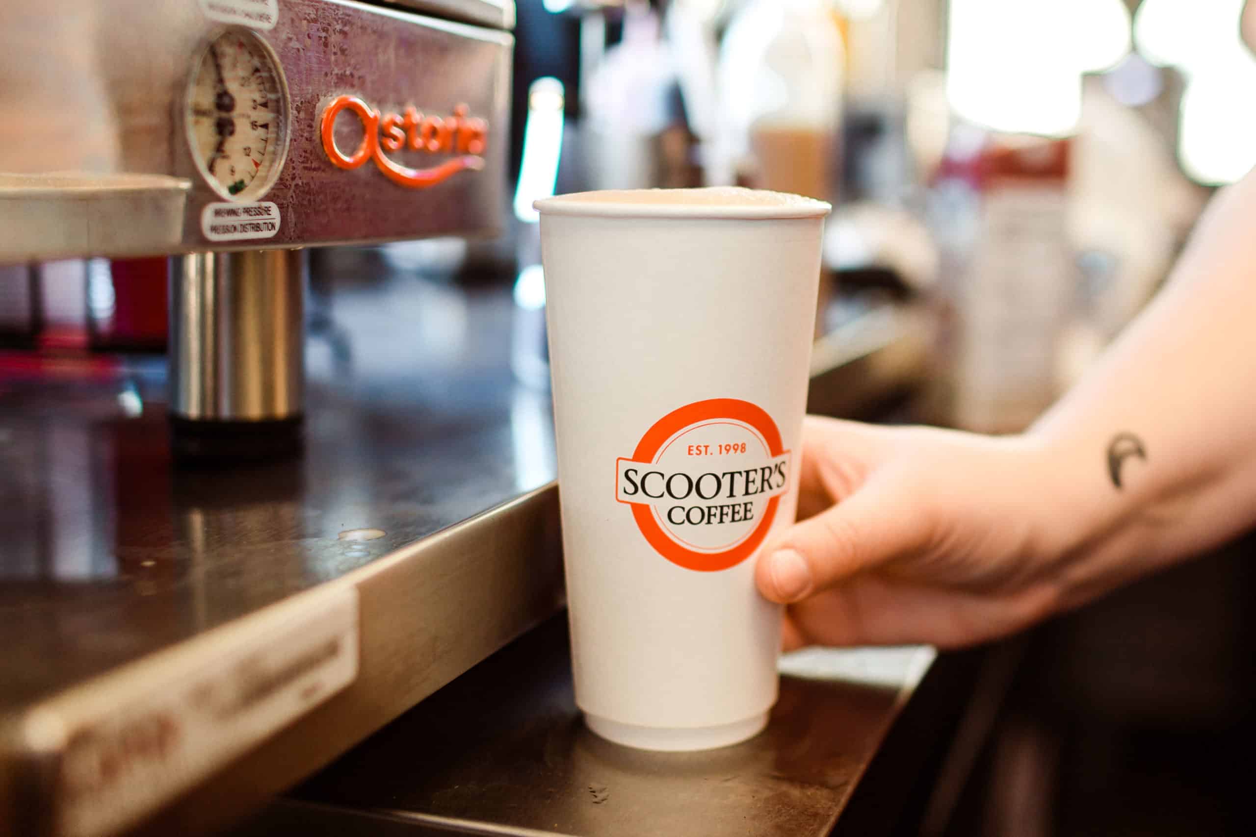 A Scooter's Coffee branded cup on an espresso machine.