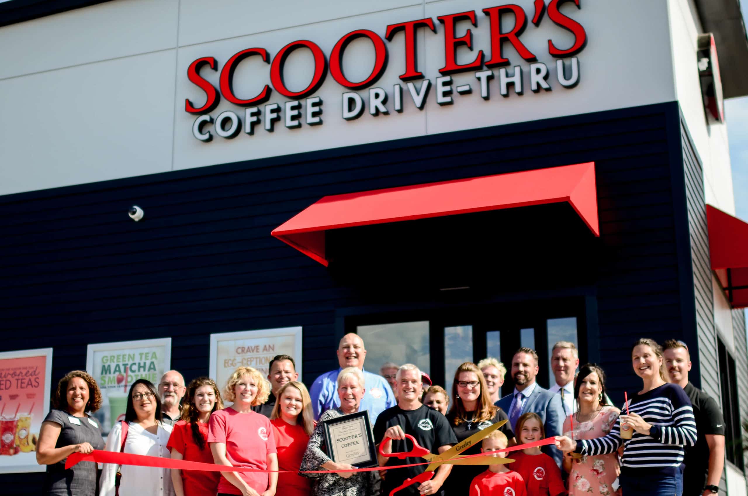 A group of happy people celebrating the opening of a new Scooter's Coffee franchise.