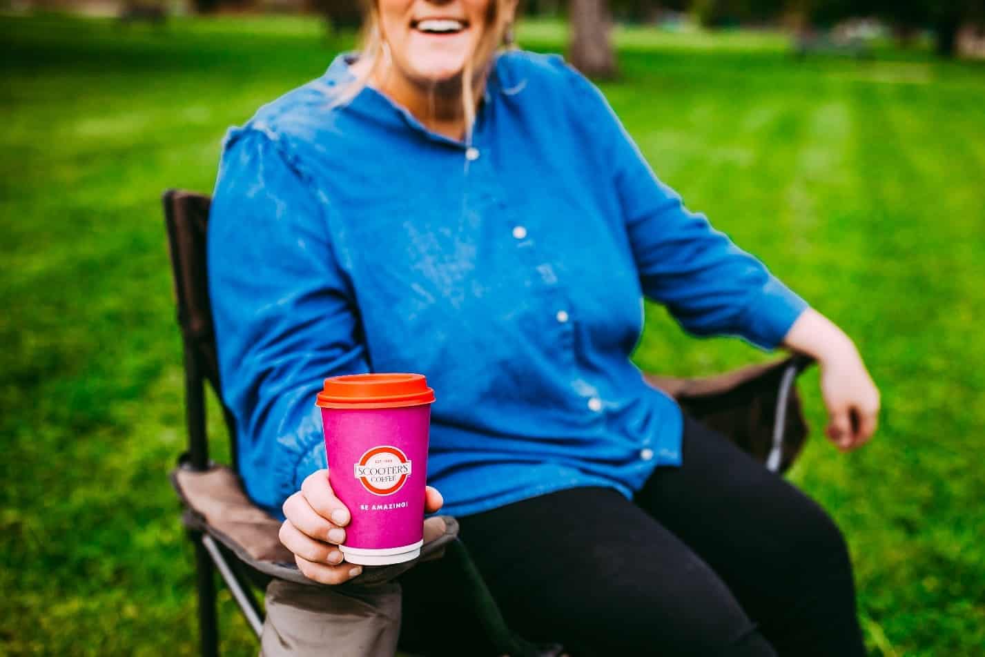 Woman sitting outside with Scooter's Coffee cup