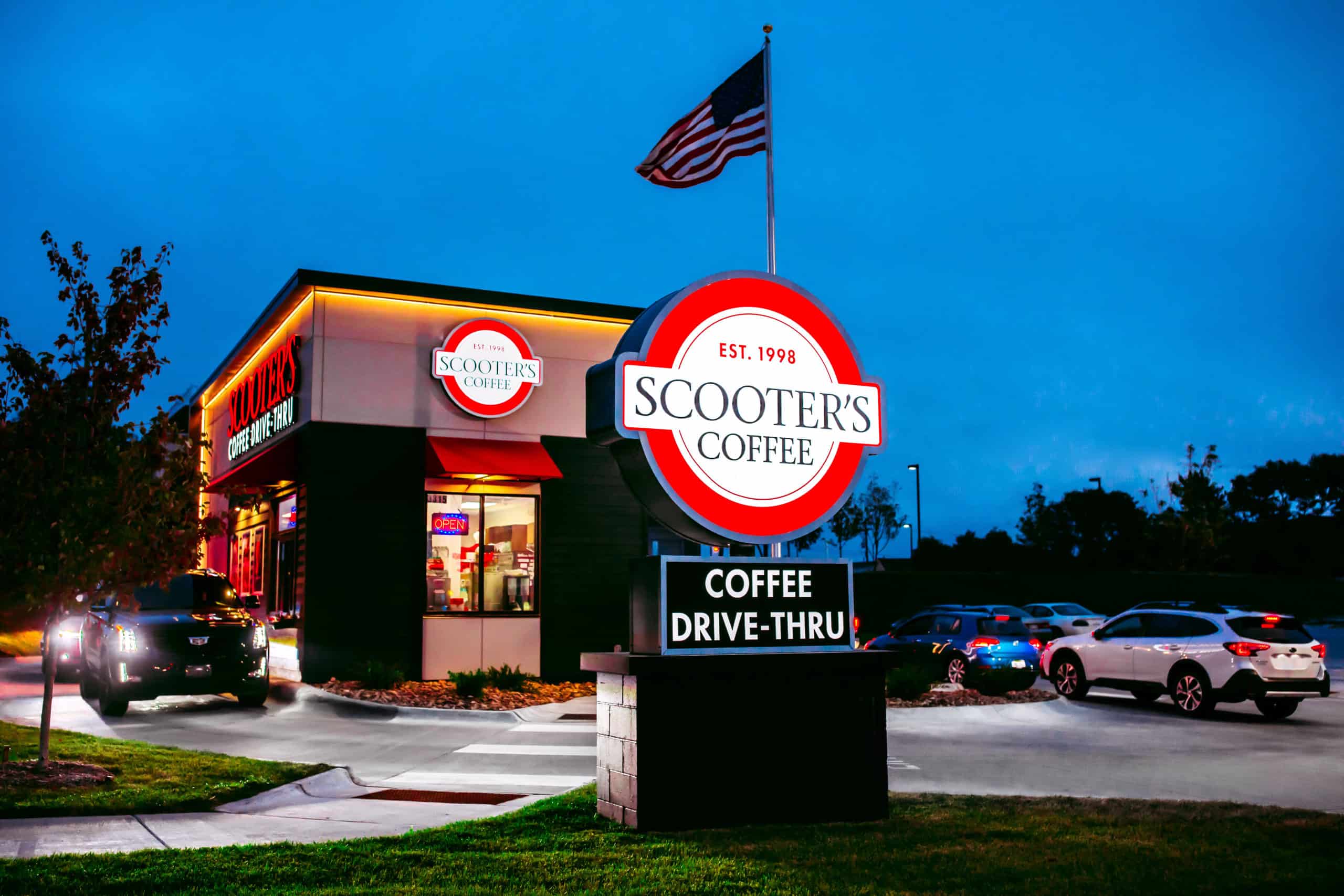 A Scooter's Coffee drive-thru coffee kiosk with an American flag.