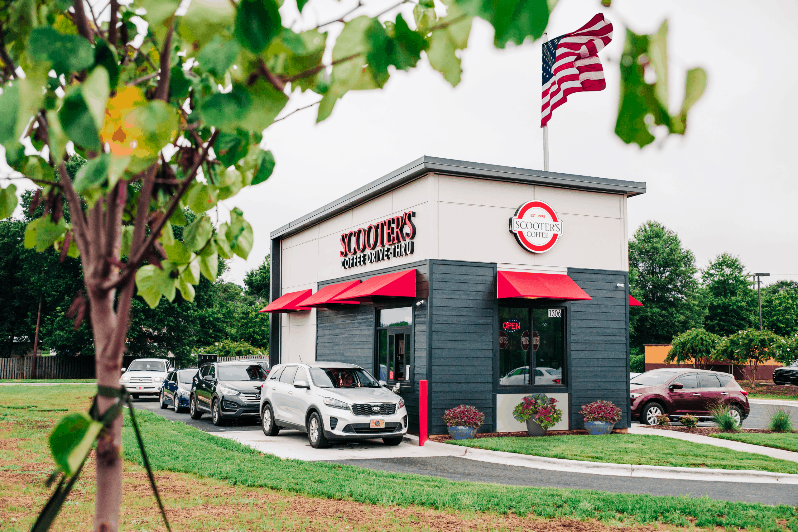 A Scooter's Coffee drive-thru coffee kiosk with an American flag.