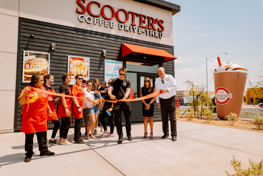 Grand opening in front of a Scooters kiosk with the staff cutting a ribbon